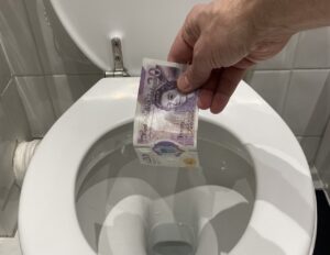 Photo of hand throwing money down toilet