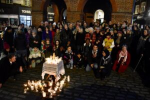 Crowd of people standing and sitting around a group of candles